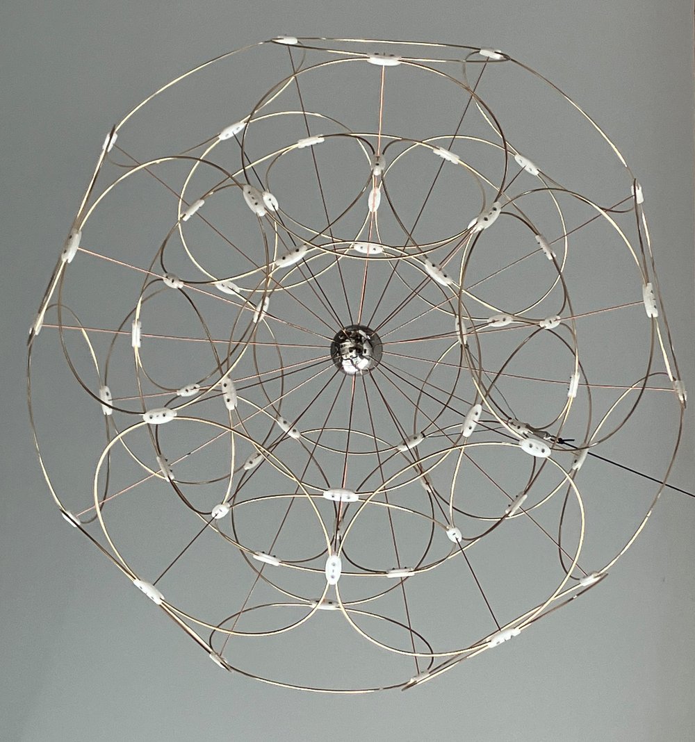 A hanging sculpture made form circular metal rings with plastic joints arranged as a dodecahedron nested in an icosahedron