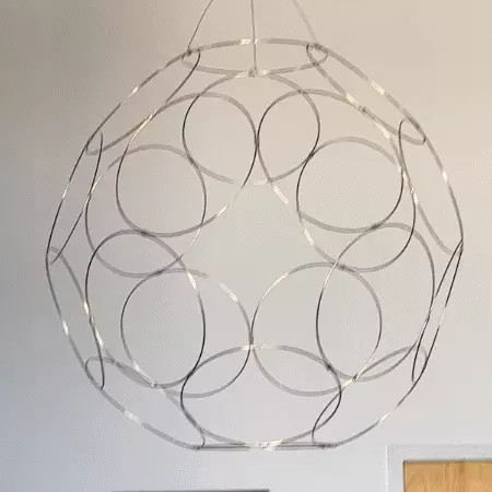 a motion image of a slowly rotating hanging sculpture made of circular metal rings arranged in a dodecahedral pattern