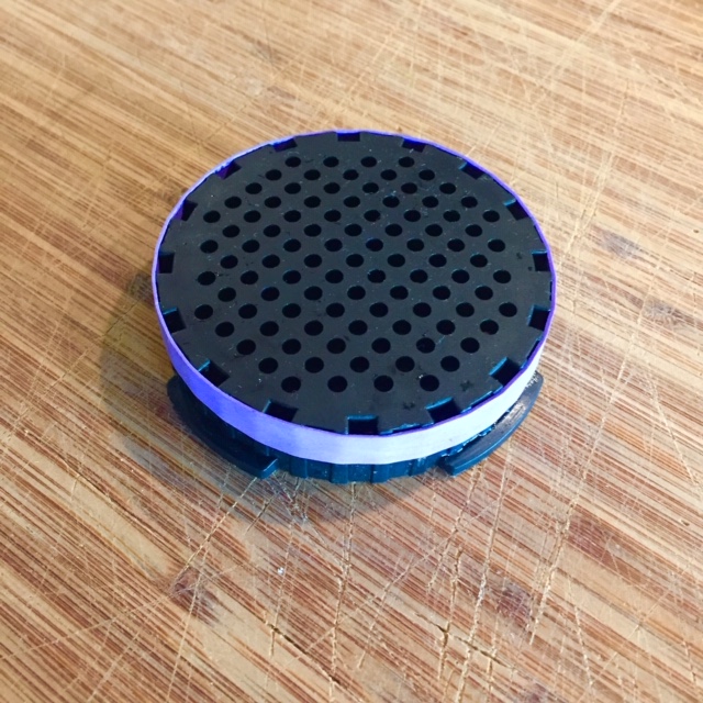 AeroPress strainer with purple rbber band stretched around the top